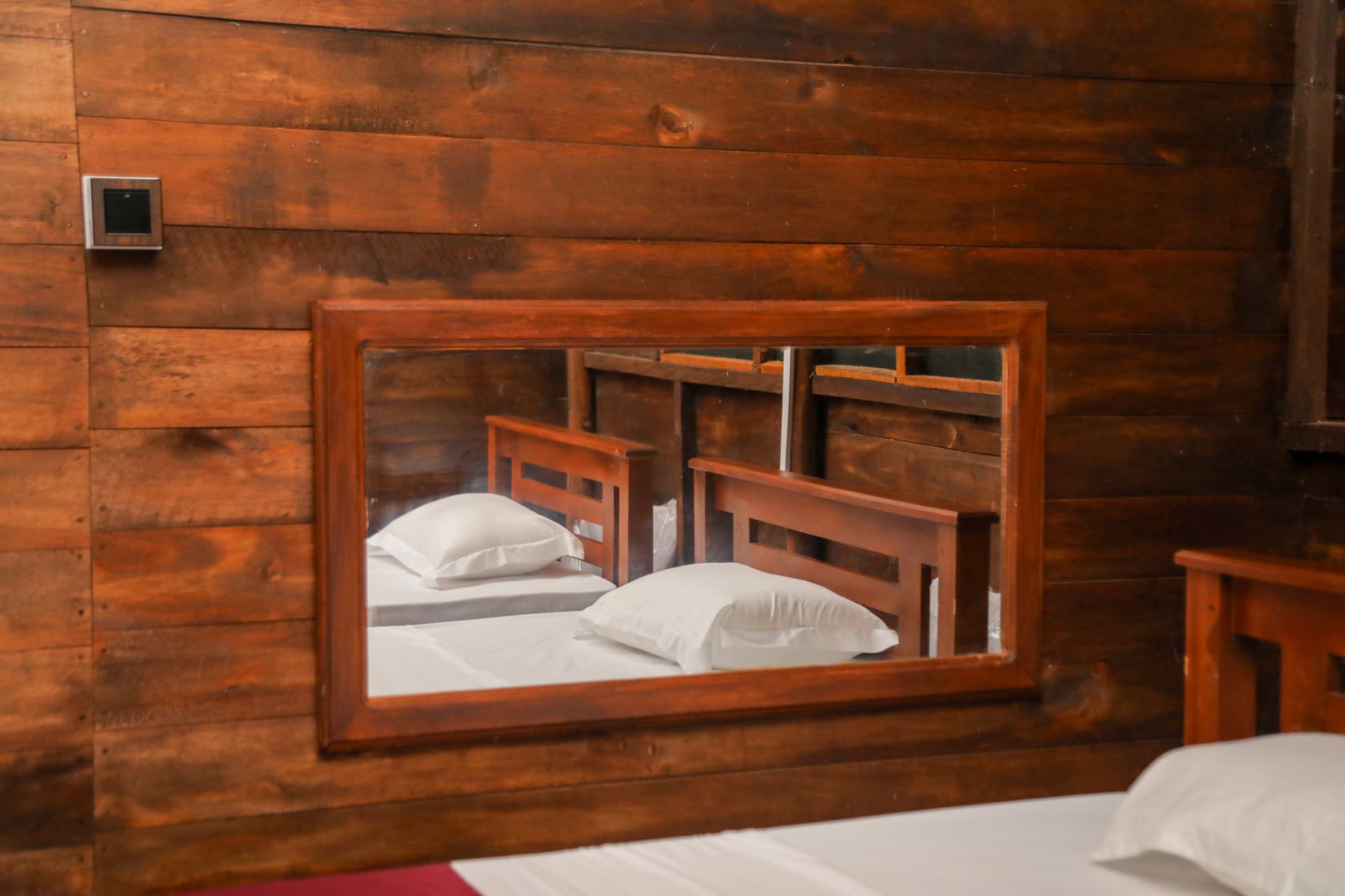Bedroom with a large vanity mirror reflecting the warm wooden interior and twin beds — a cozy retreat at Nature Win Yala.