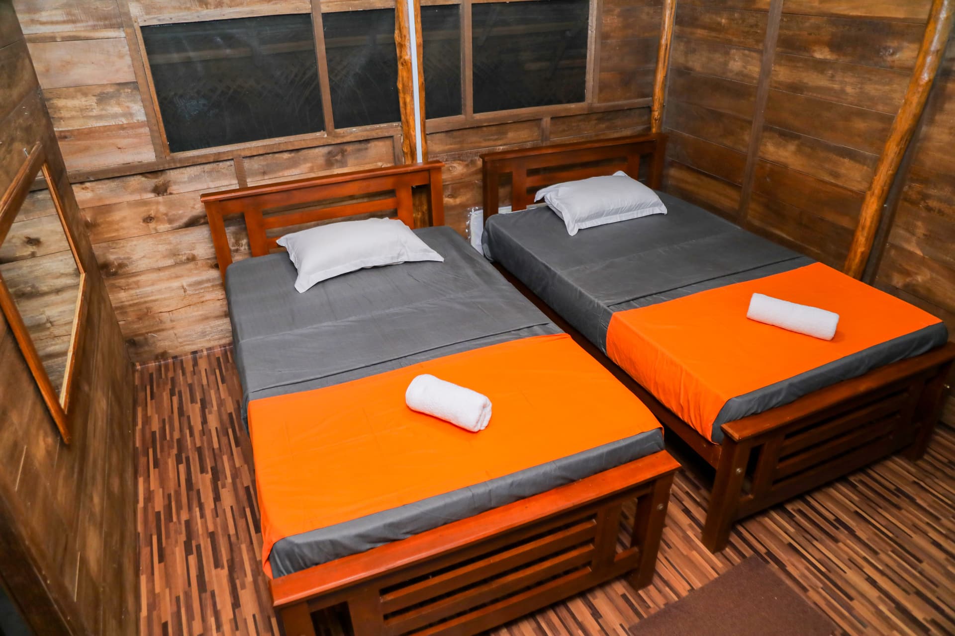 A comfortable double bedroom with a ceiling fan and a window opening to the wooden veranda — rest deeply at Nature Win Yala.